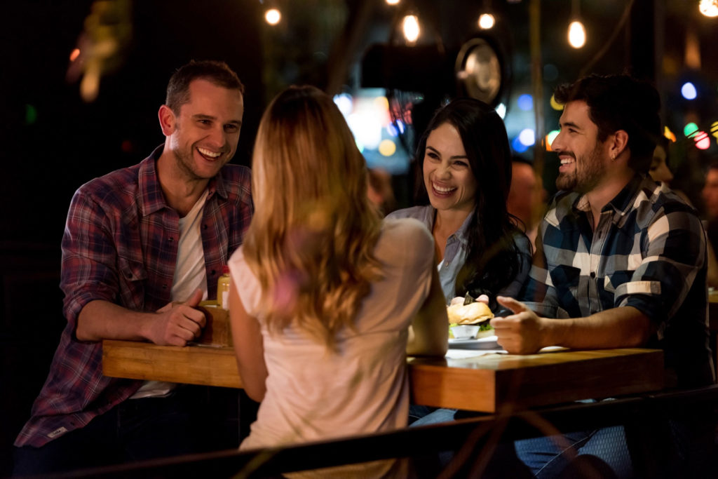 Bilde av fire stk som koser seg og smiler på pub